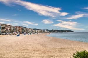 a sandy beach with buildings and the ocean at Apartament Yaco 2 in Lloret de Mar