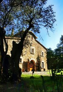 a large stone building with a tree in the foreground at El Revolt de Martís in Esponellá