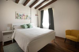 a bedroom with a white bed and a yellow chair at La Ginestra Appartamenti e Camere in Mossa