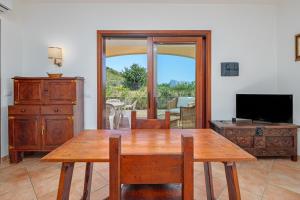 a dining room with a wooden table and a television at New Villa Carmen in San Teodoro
