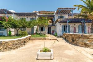 a house with a stone wall and a yard at La Casa Tinos 22 in Tinos