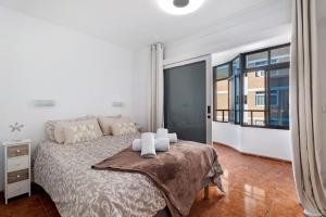 a white bedroom with a bed and a large window at Tamaragua in Candelaria