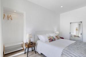 a white bedroom with a bed and a mirror at Cantinho D'Amy in Arcos de Valdevez