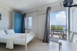 a bedroom with a white bed and a balcony at Giorgio studios-apartments 2 in Nikiana