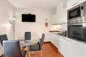 a kitchen with a glass table with chairs and a television at Ninho Gaivota in Porto Moniz