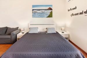 a bedroom with a bed and a couch at Ninho Gaivota in Porto Moniz