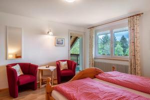 a bedroom with two red chairs and a bed and a window at Haus Scherer in Sankt Peter +84 photos