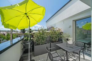 eine Terrasse mit gelbem Sonnenschirm, Tischen und Stühlen in der Unterkunft Katharinenbergblick in Endingen