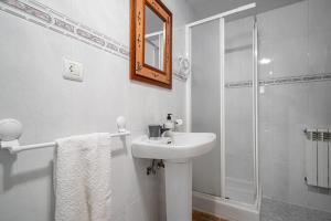a white bathroom with a sink and a shower at Lorences D in Caunedo