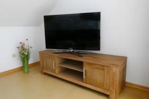 a flat screen tv sitting on top of a wooden entertainment center at Ferienwohnung Geistalblick in Neuenstein