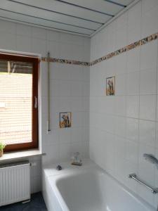 a white bathroom with a tub and a window at Ferienwohnung Geistalblick in Neuenstein +11 photos