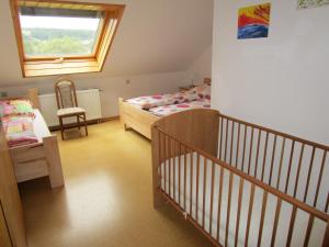 a small room with two beds and a crib at Ferienwohnung Geistalblick in Neuenstein
