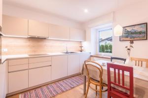 a kitchen with white cabinets and a table and chairs at Appartement Rosa Seis in Kastelruth