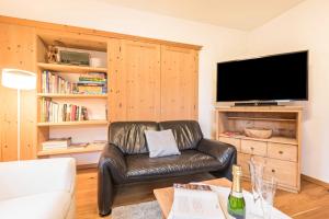 a living room with a leather couch and a flat screen tv at Appartement Rosa Seis in Kastelruth