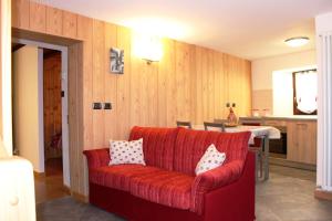 uma sala de estar com um sofá vermelho com almofadas em Maison Leveque em Brusson