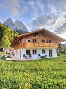 a large wooden house with mountains in the background at Ferienwohnung Bergenzian in Grainau