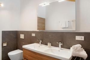 a bathroom with a sink and a toilet and a mirror at Ferienwohnung Bergenzian in Grainau +17 photos