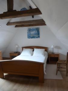 a bedroom with a bed with white sheets and wooden ceilings at Maison Typique Au Calme in Coubisou