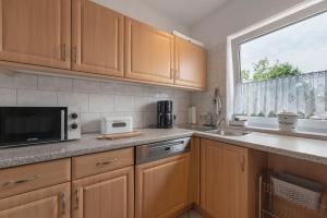 a kitchen with wooden cabinets and a microwave and a window at Bella Casa in Sankt Wendel