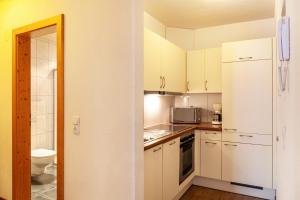 a kitchen with white cabinets and a white refrigerator at Alpenflora 2 in Ischgl +22 photos