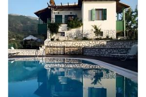 a villa with a swimming pool in front of a house at Villa Milia in Agios Nikitas