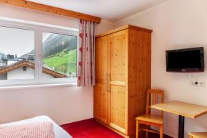 a bedroom with a bed and a tv and a window at Alpenflora 2 in Ischgl