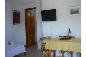 a dining room with a table and a tv on a wall at Villa Milia in Agios Nikitas
