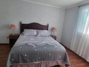 a bed in a bedroom with two lamps and two windows at Casa campo Quillota in Quillota