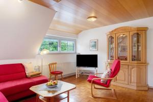 a living room with a red couch and a tv at Haus Scherer in Sankt Peter