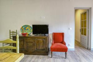 a living room with a tv and a red chair at Apartamento Bajo 3 in Begur