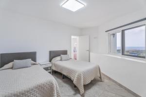 two beds in a white room with a window at Casa Miramar in Frontera