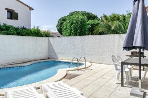 a swimming pool with a table and chairs and an umbrella at Casa Saguer in L'Escala