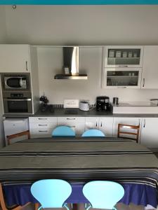 a kitchen with a table and some blue chairs at Maison Amalur in Arcangues