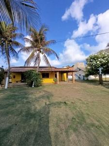 a yellow house with a palm tree in front of it at Casa Amarela - Guajiru in Trairi