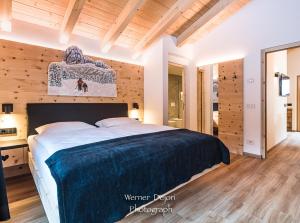 a bedroom with a large bed with a wooden wall at Piciulei Pitl in Selva di Val Gardena +26 photos