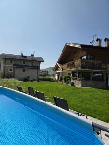a swimming pool with chairs in front of a house at Piciulei Pitl in Selva di Val Gardena