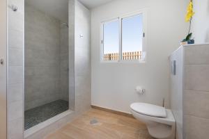 a white bathroom with a toilet and a shower at Rincón del olivar in Fuerteventura +19 photos