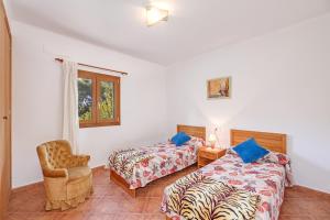 a bedroom with two beds and a chair at Camí d'es Torres in Portopetro