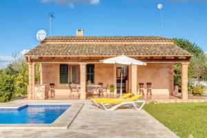 a house with a pool and a patio with chairs and an umbrella at Camí d'es Torres in Portopetro