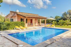 a villa with a swimming pool in front of a house at Camí d'es Torres in Portopetro