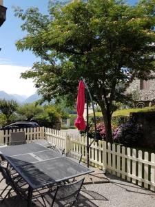 a table with a red umbrella next to a fence at Gite du Pibeste - 8 pers in Ouzous