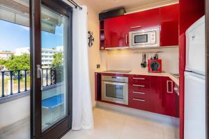 a kitchen with red cabinets and a large window at Neo in Cala Ratjada