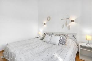 a white bedroom with a bed with two pillows at Sa Calma House in Cala en Bosc +17 photos