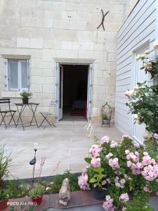 a patio with pink flowers in front of a building at Chambre Hirondelle in L'Ile-Bouchard