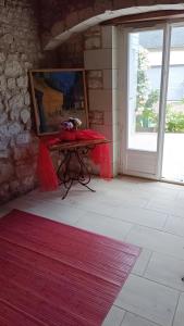 a room with a table with a painting and a window at Chambre Hirondelle in L'Ile-Bouchard