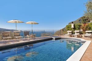 a swimming pool with chairs and umbrellas at Rustico Spagnol 4 in Tignale