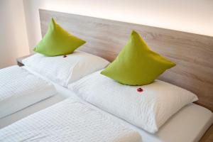 two white beds with green pillows on top of them at Ferienwohnung Daniela in Merano