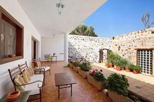 a patio with chairs and tables and a stone wall at Las Raíces in Pájara