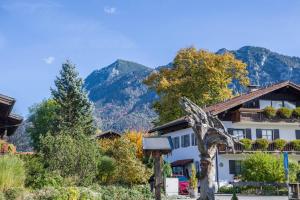 a building with a tree in front of it with mountains at Ferienwohnung Marinas Alpenblick in Inzell