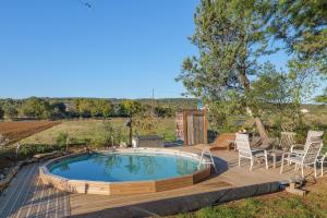 a hot tub on a deck with chairs and a table at Chambre La Louve in Banne